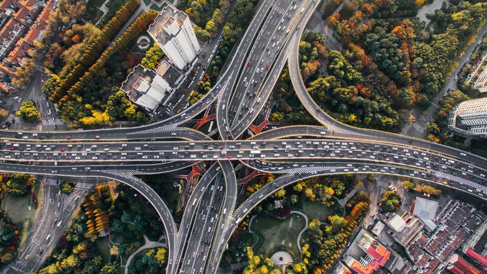 Luftaufnahme eines Verkehrsknotenpunkts mit mehreren Überführungen, symbolisiert Infrastruktur und Vernetzung.