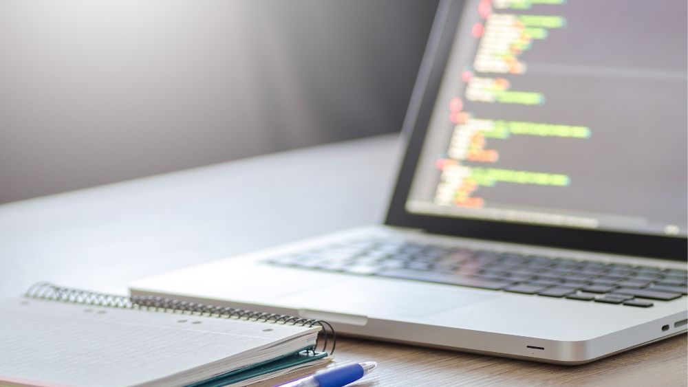 Laptop mit Code auf dem Bildschirm auf einem Schreibtisch stehend